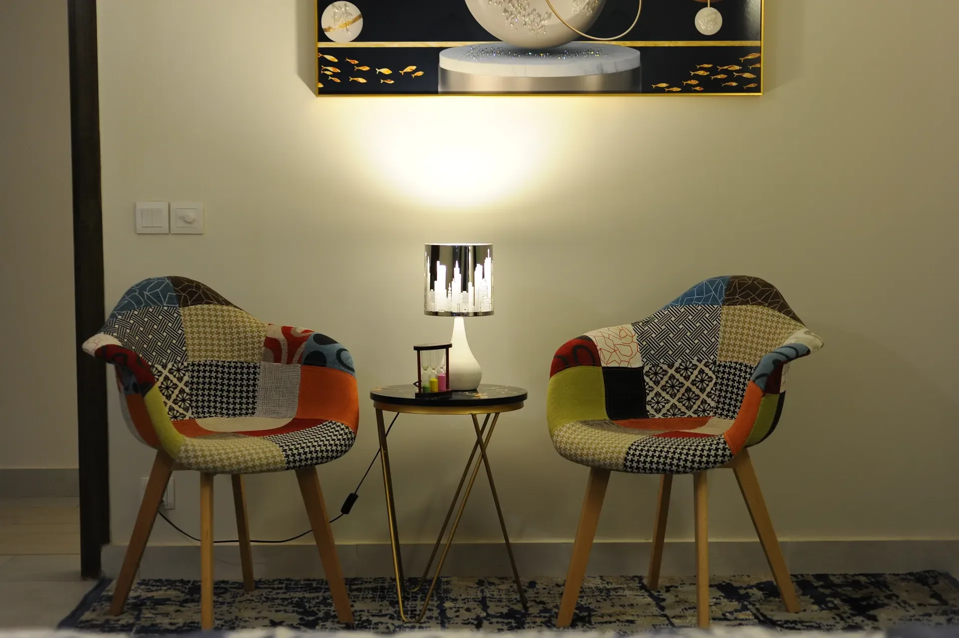 A pair of patterned lounge chairs either side of a lamp-lit side table.